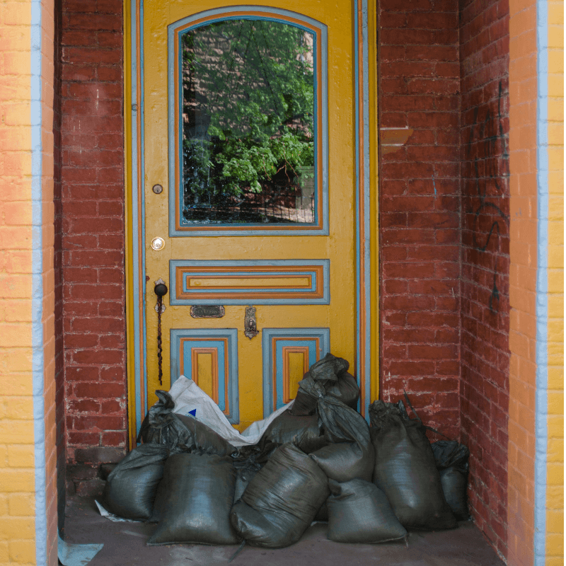 Yellow front door protected from flooding by sand bags